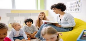 Children sitting on the floor listening to a story being read by their teacher