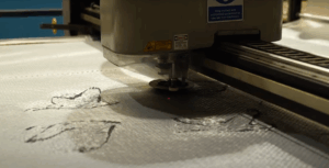The Gerber cutter laser cutting the design pieces out of the mat