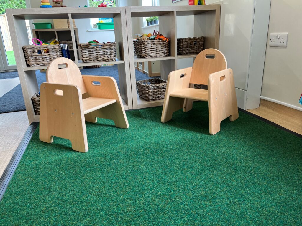 Close up of loose lay mat in the reading area with chairs on it and a bookcase behind it